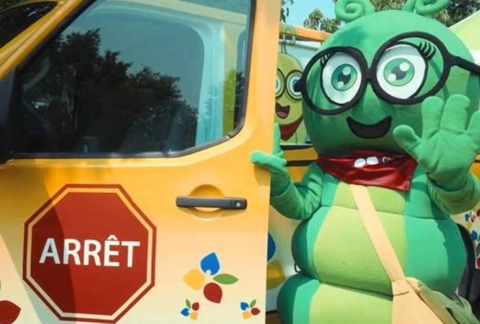 Camille La chenille, la mascotte du conseil devant son bus jaune du CECCE